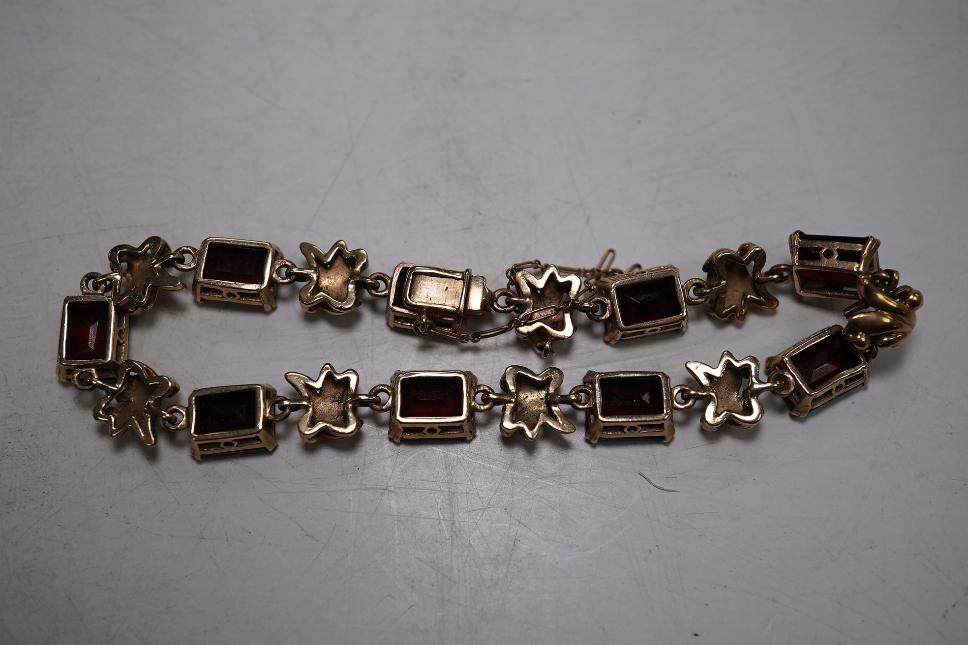 A yellow metal and nine stone emerald cut garnet? set bracelet, 18cm, gross weight 16.5 grams. Condition - fair